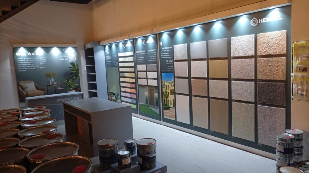 The interior of a Hempel Paints paint store and showroom, showing a large wall display of color and texture samples for exterior paint and decorative coatings.