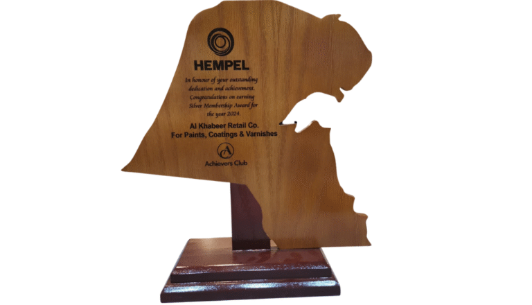 A wooden award shaped like the map of Kuwait, featuring the Hempel logo and honoring Al Khabeer Retail Co. with the Silver Membership Award for 2024.
