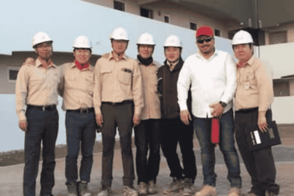 مجموعة من الطاقم الفني ومهندسي أصباغ همبل يرتدون خوذات السلامة ومعدات الوقاية في موقع أحد المشاريع الصناعية.
