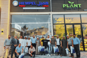 مجموعة من موظفي وعملاء أصباغ همبل يقفون أمام معرض تجاري في الكويت.