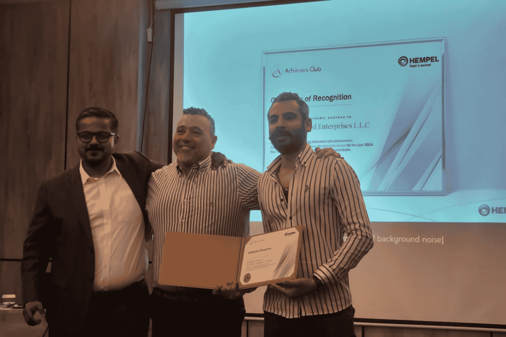 Three professional men posing at an indoor awards event.